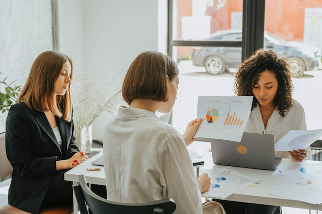 Three women analyze financial reports