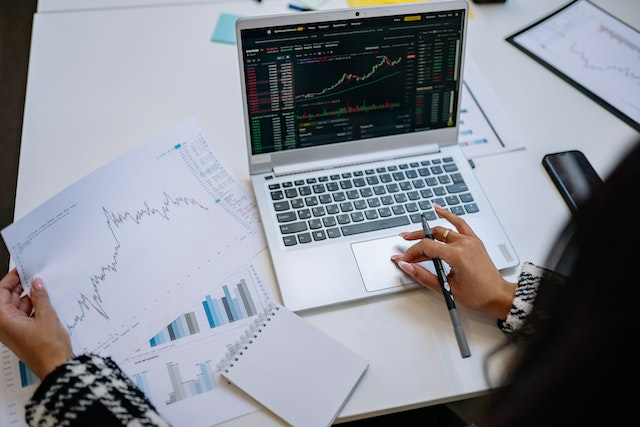 Woman compares financial report from paper and screen